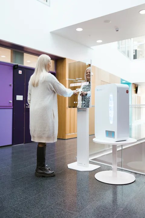 A patient using a DentView self-care station with the kit dispenser in a health centre lobby